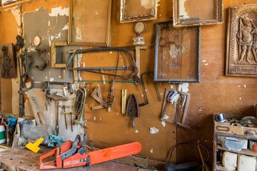 Old carpentry tools in home workshop. Repair of agricultural machinery. Old planers and drills on workshop wall.