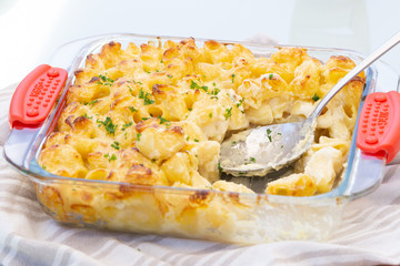 Macaroni and cheese in transparent dish on cotton towel on the table. There is a spoon inside it. Homemade vegetarian lunch or dinner. Close up. 