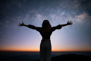 Fototapeta na wymiar Silhouette of young traveler open arm and watching the star and milky way on the top of the mountain and enjoying with beautiful view of the stars before sunrise on top of the mountains.