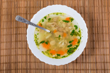 Chicken noodle soup in bowl with spoon, top view closeup