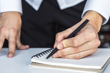 Man writes with a pen in diary in a sunny office, business and education concept. Close up