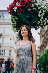Beautiful girl walking in the summer city. Girl in a summer dress on a background of flowers. Young...