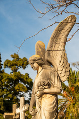 großer Engel mit Blumen im Arm auf einem Friedhof in Spanien
