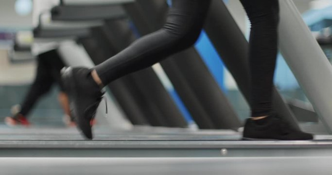 Young woman walking on a treadmill at gym.Warm up or cool down.Legs side view close shot, lower body detail. Woman training at fitness center. Woman exercising cardio workout