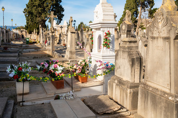 viele bunte Blumen vor einem Grabstein auf einem Friedhof in Spanien