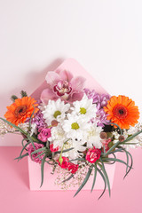 Obraz na płótnie Canvas Bouquet of flowers in an original box on a white-pink background.