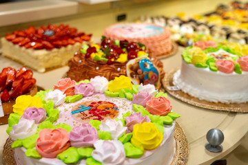 Cakes and pastries in a shop window. Pastry shop with variety of donuts, Creme brulee, cakes with fruits and berries