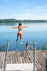 Fototapeta na wymiar children dive into the water from pier