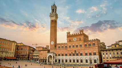 Fototapeta premium Siena, Toscana, Włochy - wrzesień 2014: Niesamowity zachód słońca z widokiem na dzwonnicę Torre del Mangia