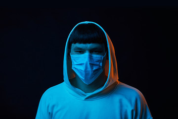 portrait young guy in white hoodie  on medicine mask on black background