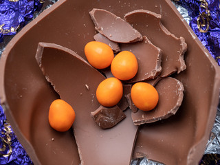Five mini, chocolate, orange eggs inside the remains of a broken Easter egg