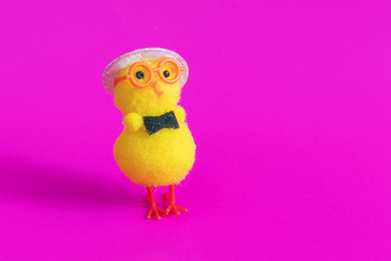 Toy chicken in glasses and hat on a pink background