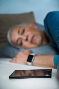 Sleep Apps - Tech-savvy Senior Woman Sleeping In Bed, Using Smart Phone And Smart Watch To Improve Her Sleeping Habits