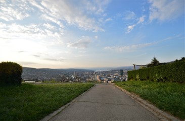 Fototapeta premium Footpath in the Waid with a view of the city of Zurich Switzerland in the morning with the Alps in the background