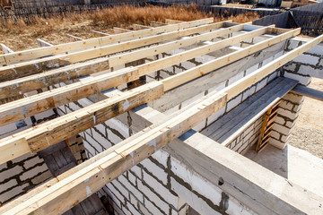Under construction house walls made from white aerated autoclaved concrete blocks. Woods elements and components of the construction of roof. Ceiling beams of natural eco-friendly materials. top view