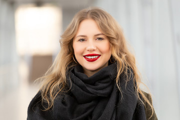 Fototapeta premium Closeup portrait of a happy young woman smiling. Stylish fashion portrait woman. Posing in the city. Beautiful girl in autumn green coat and black scarf poses in an overhead pedestrian crossing.