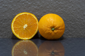 Navel oranges (Citrus sinensis) in natura on mirrored surface and light background