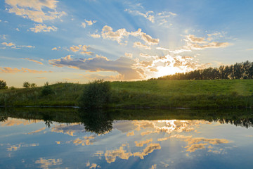 Fototapeta na wymiar Summer evening landscape with reflection of clouds in the lake