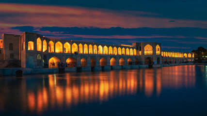 Isfahan, Iran - Mai 2019: Khaju-Brücke über den Zayandeh-Fluss in der Abenddämmerung mit Lichtern während der blauen Stunde