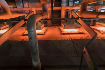 Glassworks. Glass industry. Burning blanks of glass bottles in an industrial stove. Hot bottle...