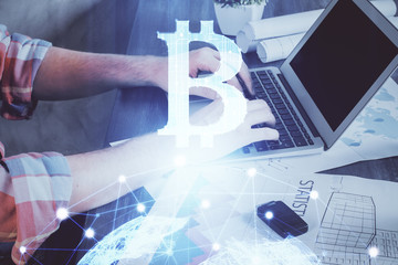 Crypto currency theme hologram with businessman working on computer on background. Concept of blockchain. Multi exposure.