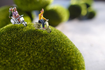 Group of traveler miniature people figures ride motorcycle, green concept