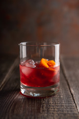Red traditional old fashioned cocktail with orange zest on the rustic background. Selective focus. Shallow depth of field.