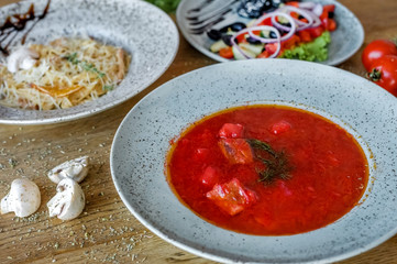 carbonara salad and borsch in turquoise plates stand on the table
