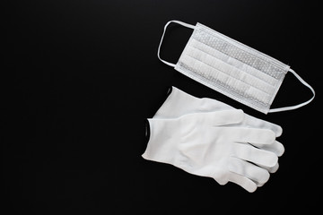 Prevention and protection against the spread of viruses and diseases. White antibacterial medical mask and gloves on a black background with copyspace