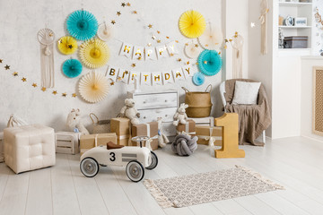 Birthday decorations with balloons, gifts, toys, garlands and candy for yearling, little baby party, selebration on a white wall background. Yellow and teal Decor elements.