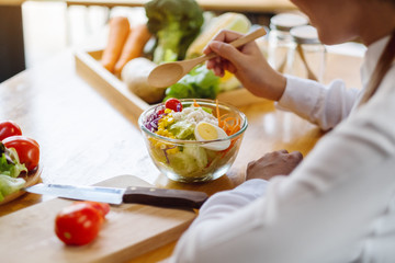 Closeup image of a female chef cooking and holding a bowl of fresh mixed vegetables salad to eat in kitchen