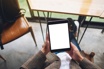 Top view mockup image of a woman sitting and holding black tablet pc with blank white desktop screen