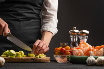 Chef slices zucchini, close-up on a background of vegetables. Cooking fresh salad. Cooking and recipe book. Useful and tasty food