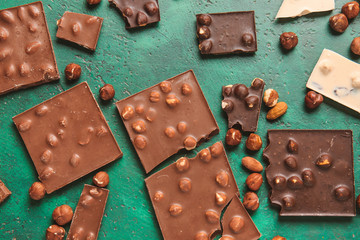 Sweet chocolate with nuts on color background