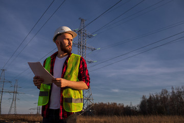 Successful engineers stand against the power pole on the blue background