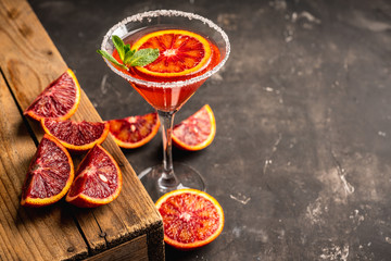 Red cocktail with bloody oranges in martini glass on the rustic background. Selective focus. Shallow depth of field.