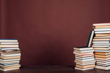 many stacks of educational books to study in the university library on a brown background