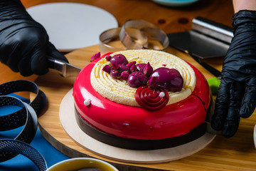 Pastry chef cuts a trendy mousse cake. Preparation of the modern dessert.