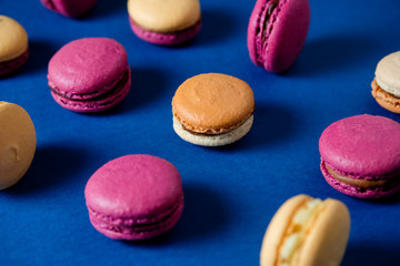 Fototapeta na wymiar Macarons pattern on blue background. Colorful french desserts. Top view.