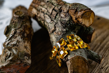Beautiful and fashionable women's jewelry, elegant large yellow stones on a gold base, square shape, hanging on the bark and wooden natural snags