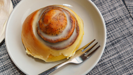 Top view of cinnamon bun on plate and fork. Coffee and dessert concept.