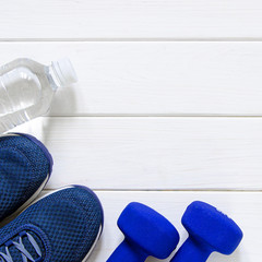 Sports set. Blue women's sneakers, blue dumbbells and white scales stand on a white background