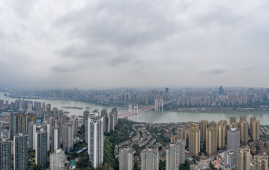 Fototapeta premium Aerial drone shot of Caiyuanba Bridge over Yangtze river and dense riverside residential building along in Chongqing, China