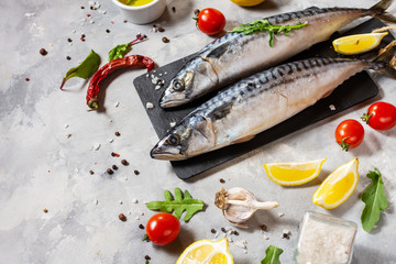 Fresh raw mackerel with lemon and spices on concrete background.