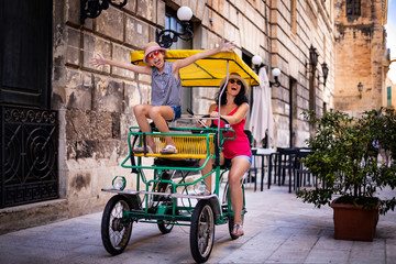 Obraz premium Tourist family having fun with tandem bike at the narrow streets of Lecce, Italy
