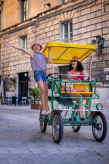 Tourist family having fun with tandem bike at the narrow streets of Lecce, Italy