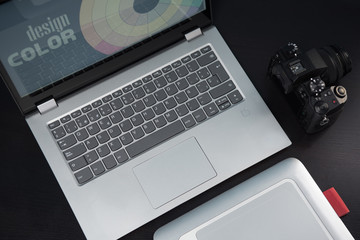 Graphic designer's desk table, laptop, camera and graphic tablet on a dark wooden table. Concept graphic design studio.