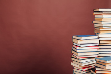 many stacks of educational books to study in the university library on a brown background