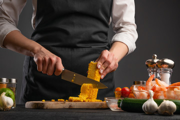 the chef cuts corn grains to prepare seafood dishes. Vegetables and proper nutrition. Recipe book....