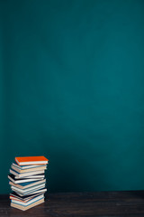 many stacks of educational books to teach in the school library on a green background